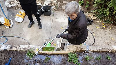 Bewohnerin gießt Blumen.
